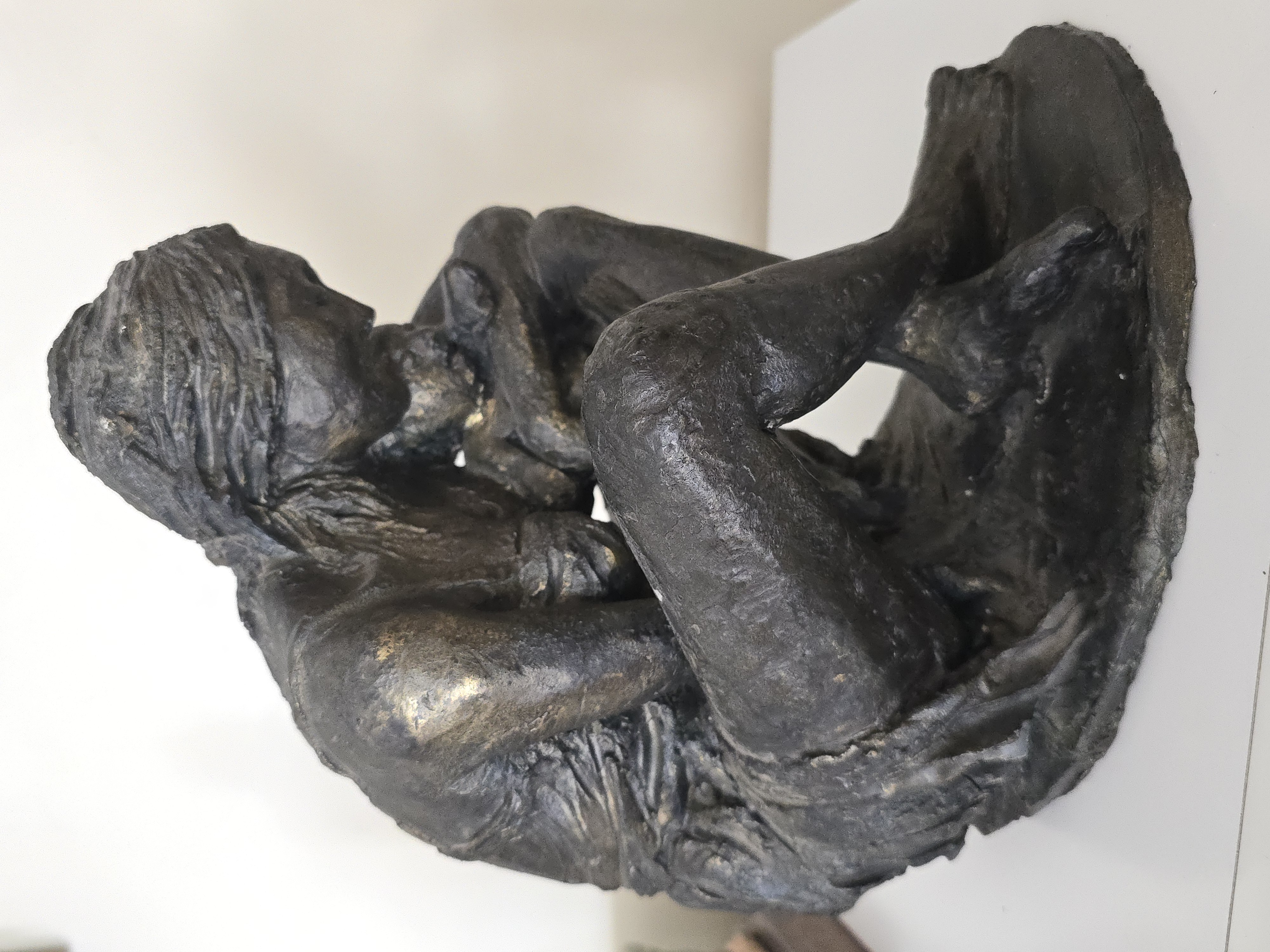 Scultura in vetroresina intitolata "Solitudine" di Klirò, raffigurante una donna raccolta che stringe un orsetto di peluche.